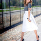 beautiful woman on a sunny day jumping in a white skirt, black heels, gray top