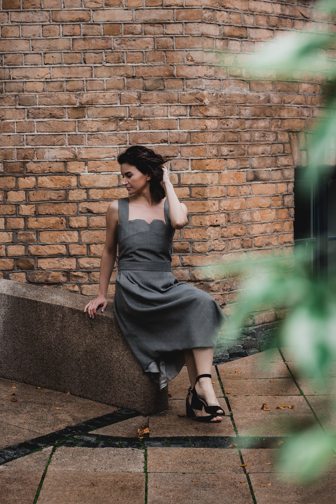 beautiful brunette on the streets in a gray two piece office dress - a corset top and a triangle skirt
