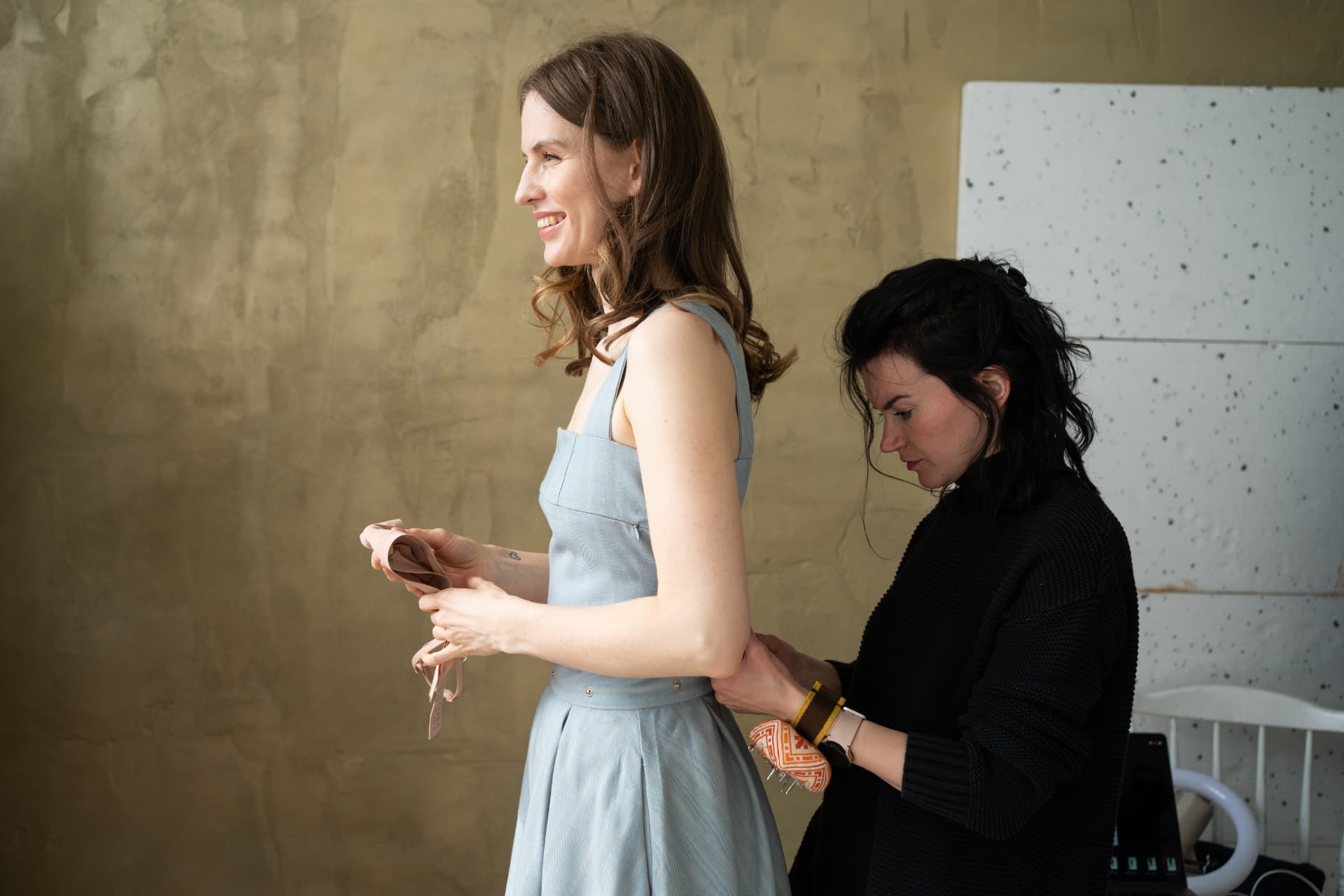 The designer fitting a pale blue nursing dress on a woman in the atelier