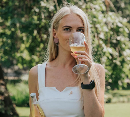 beautiful blond lady in a white top, sipping white wine