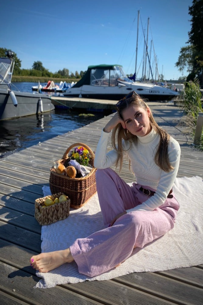 lady with pink pants and white turtleneck by the boat in sunglasses on a pic-nik