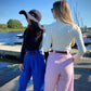 ladies with pink and blue pants and white and black turtleneck by the boat in sunglasses and a hat