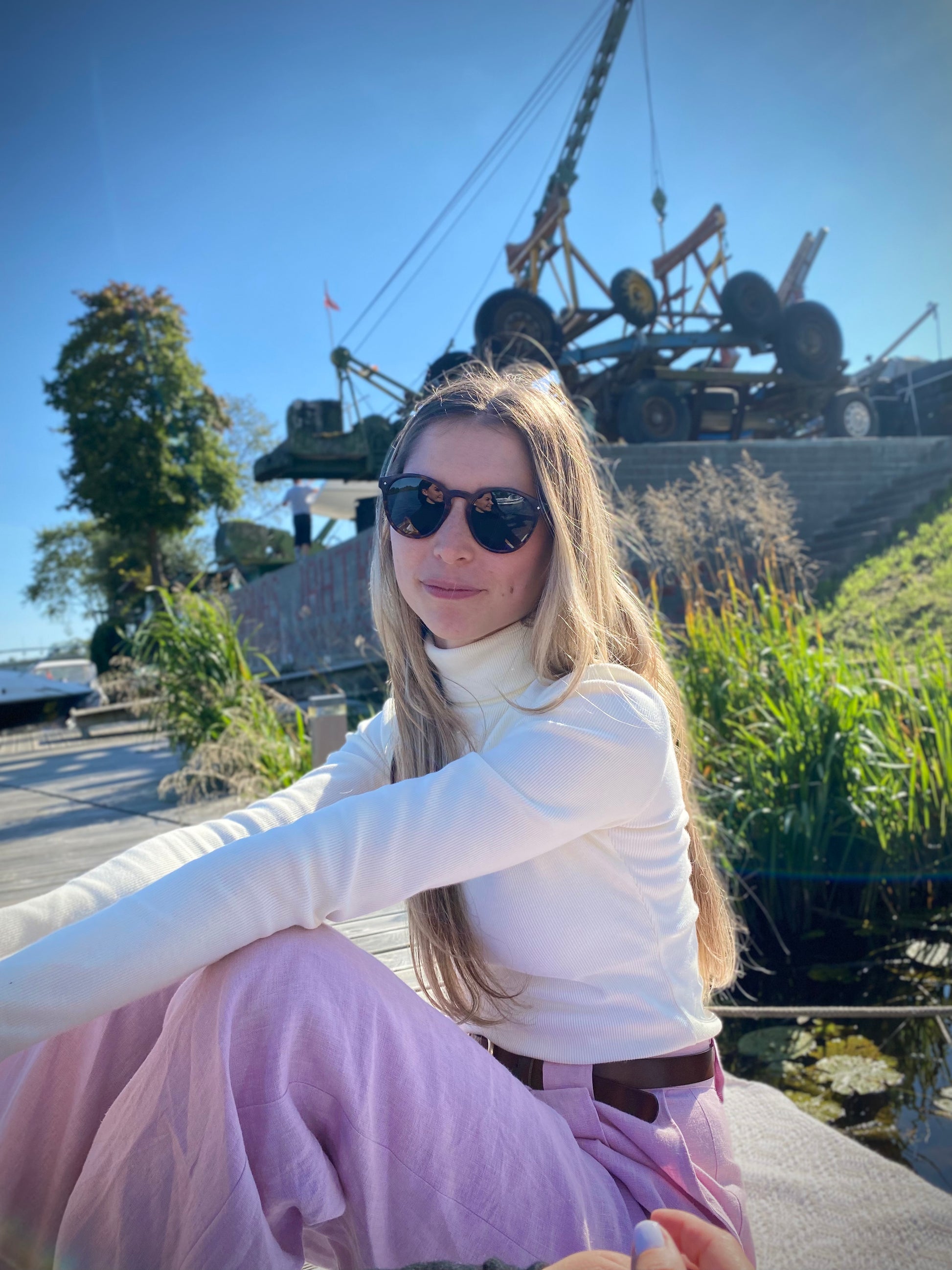 lady with pink pants and white turtleneck by the boat in sunglasses