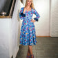 beautiful blond lady in a colorful baby blue dress and purple heels. dress with feathers on the sleeves