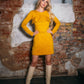 Beautiful blond woman in a mustard yellow two-piece dress with ruffle. She is wearing white boots