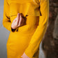 Beautiful blond woman in a mustard yellow two-piece dress with ruffle 