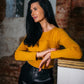 Beautiful black haired woman wearing mustard yellow top with ruffle and black leather pants