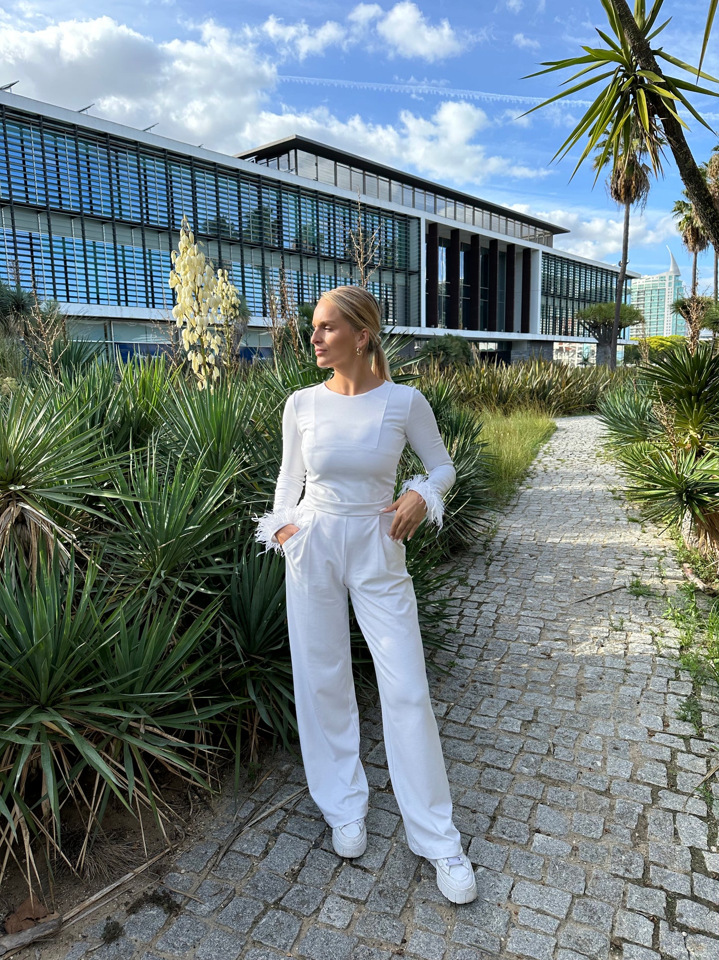 beautiful blond woman in white jumpsuit in palm trees in Portugal
