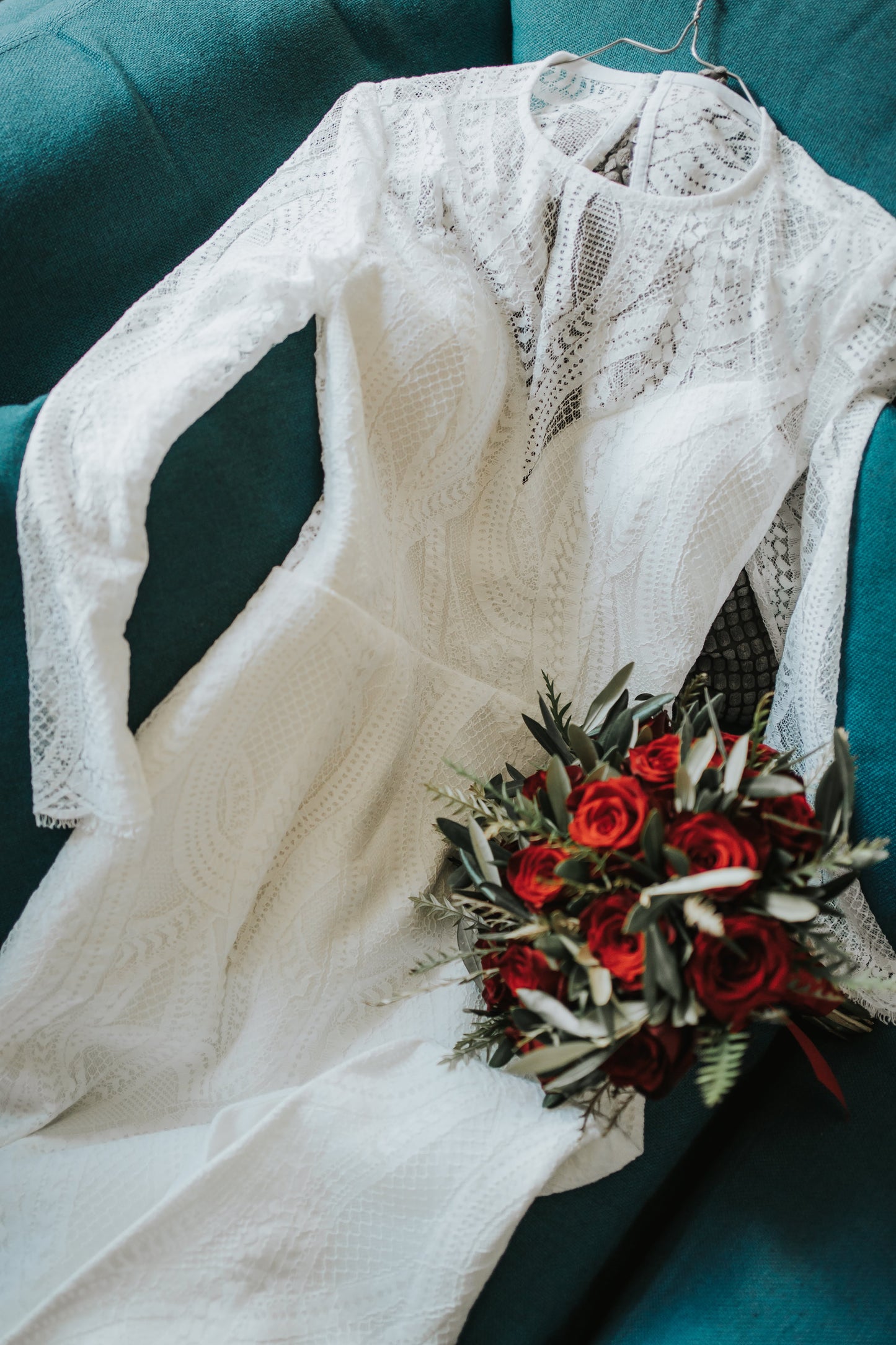 lace wedding dress on a sofa with rose bouquet