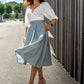 beautiful woman outside in the sunny streets, turning around in her flowy sky blue below-the-knee skirt and a white blouse