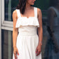 beautiful woman in a white two piece dress with corset top with a ruffle over the breast seam and long flowy skirt