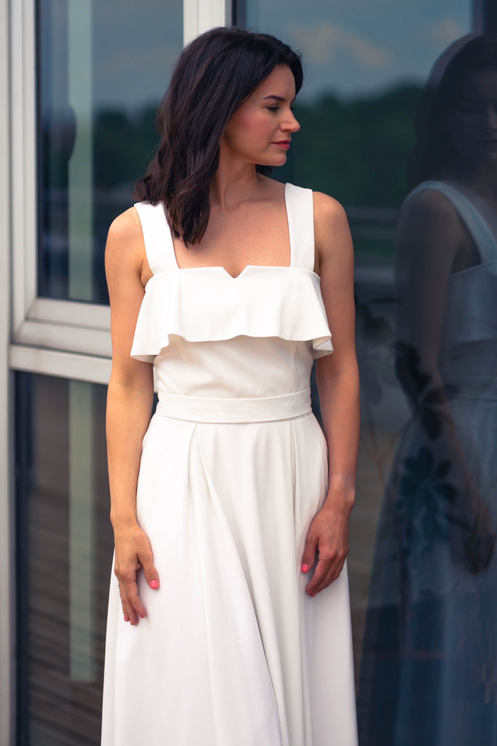 beautiful woman in a white two piece dress with corset top with a ruffle over the breast seam and long flowy skirt