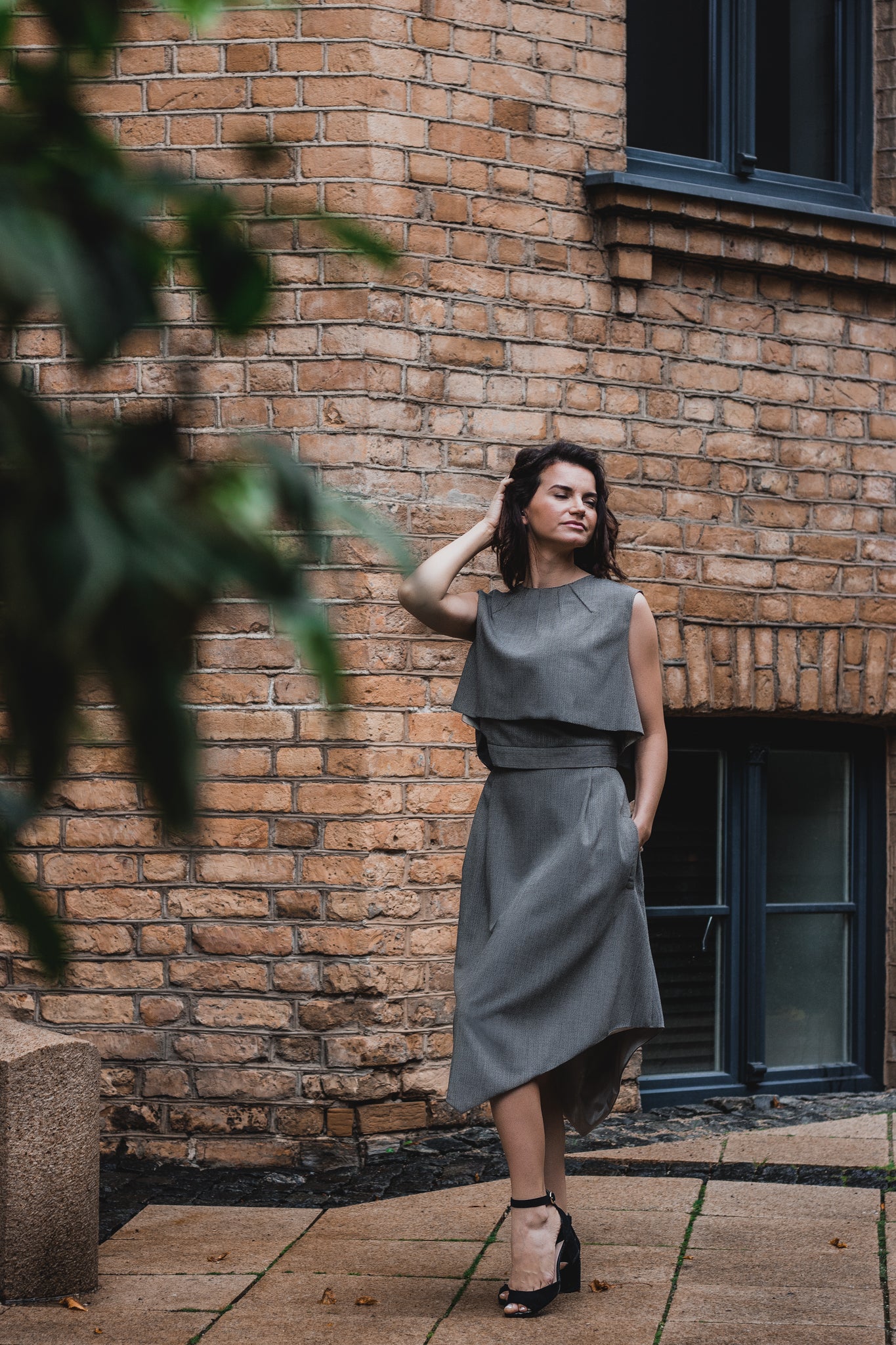 beautiful woman brunette on the streets of riga in a gray classic three piece dress
