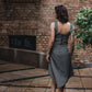 beautiful brunette on the streets in a gray two piece office dress - a corset top and a triangle skirt, this picture is made from the back and the beautiful and high-quality black tractor zipper is visible