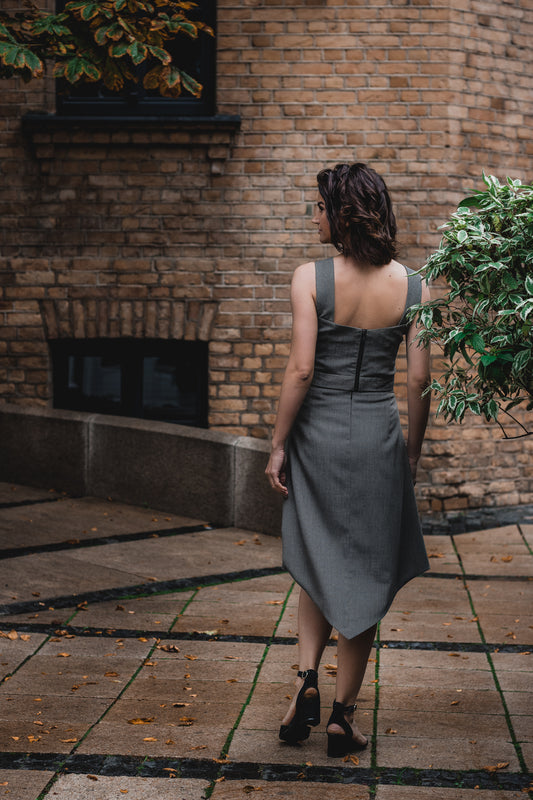 beautiful brunette on the streets in a gray two piece office dress - a corset top and a triangle skirt, this picture is made from the back and the beautiful and high-quality black tractor zipper is visible