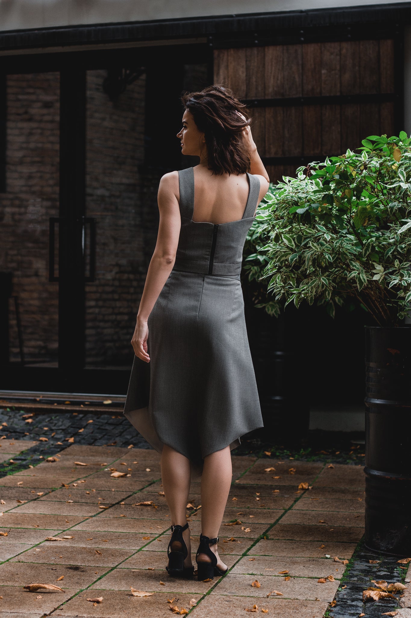 beautiful brunette on the streets in a gray two piece office dress - a corset top and a triangle skirt. the top has a cute, high quality black tractor zipper