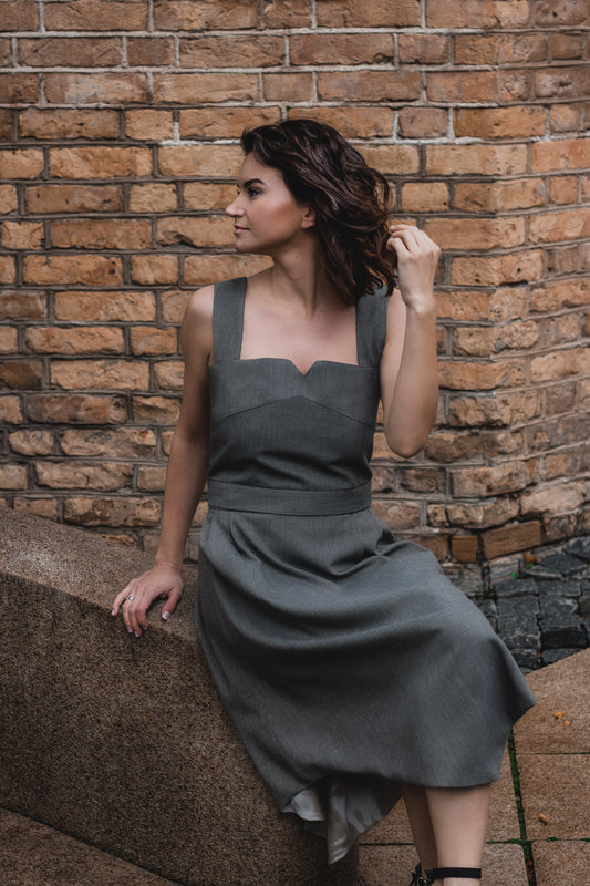 beautiful woman sitting in the streets in her gray two piece office dress consisting of a corset top and a triangle skirt