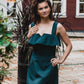 beautiful lady in an emerald green two-piece dress, that consists of a ruffled top and a mini skirt with pockets