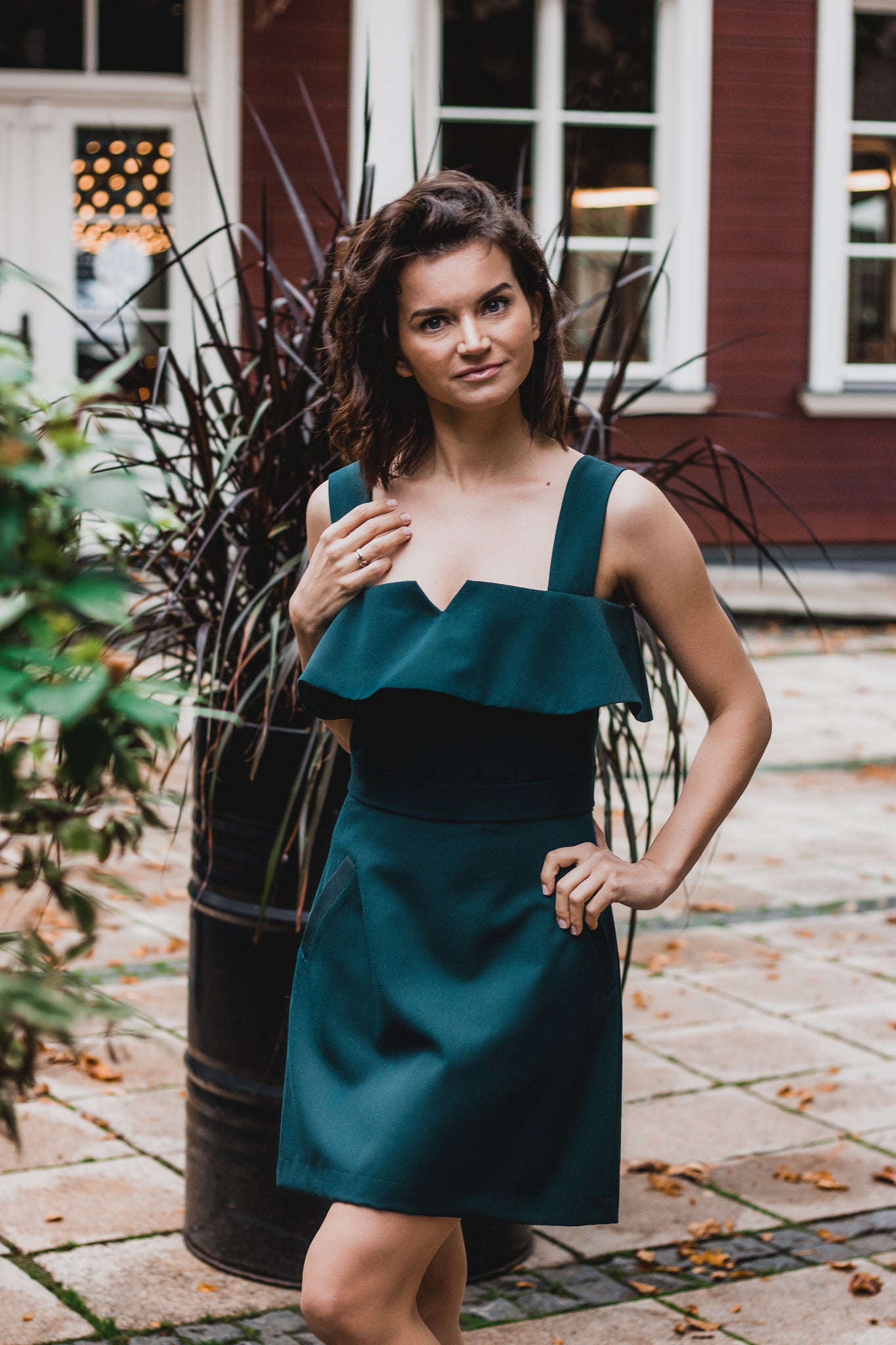beautiful lady in an emerald green two-piece dress, that consists of a ruffled top and a mini skirt with pockets