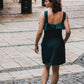 beautiful lady from the back in an emerald green two-piece dress, that consists of a ruffled top and a mini skirt with pockets