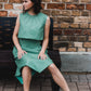 beautiful woman sitting on a bench in mint green three-piece dress set smiling over the shoulder. triangle skirt