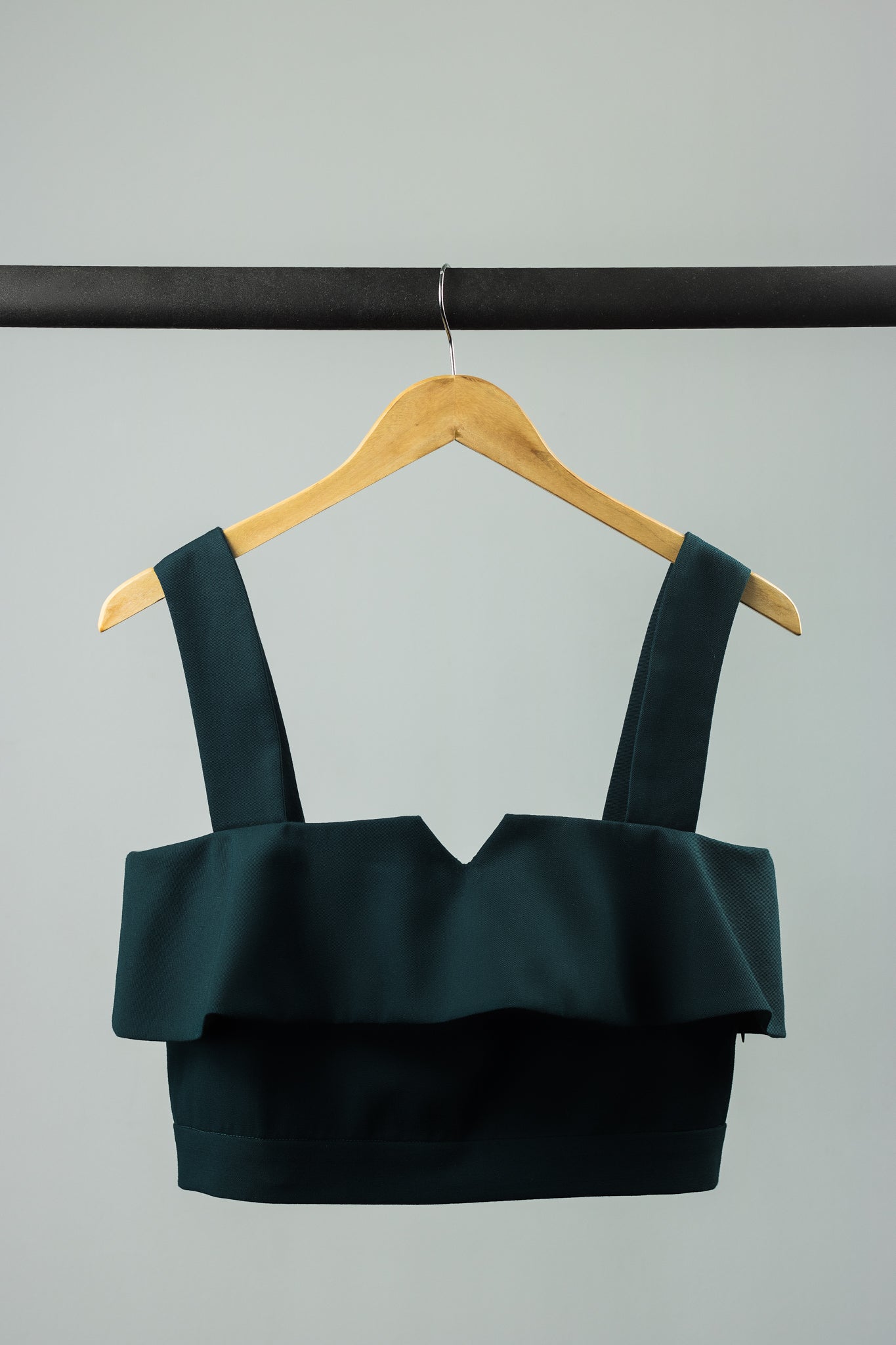 emerald green ruffled top on a garment hanger