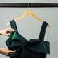 emerald green ruffled top on a garment hanger showing the nursing zipper