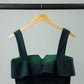 emerald green ruffled top on a garment hanger from the back