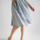 a beautiful below the knee flowy A-lined skirt made from blue wool fabric paired with pink heels. the skirt has pockets