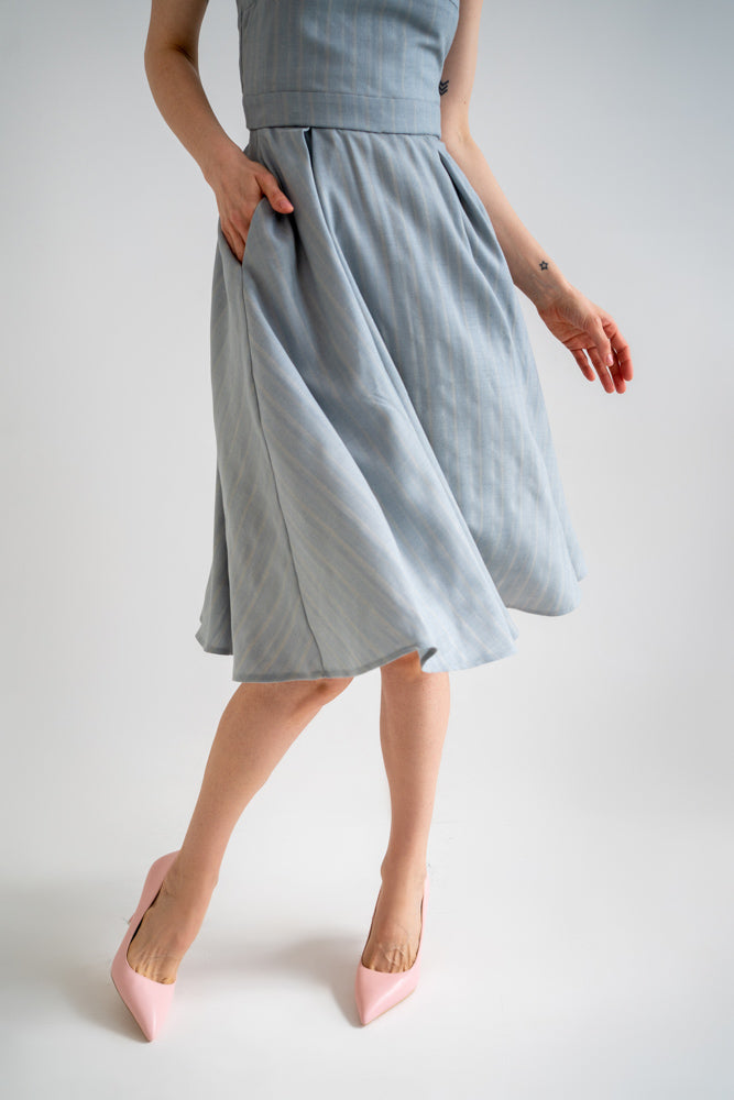 a beautiful below the knee flowy A-lined skirt made from blue wool fabric paired with pink heels. the skirt has pockets