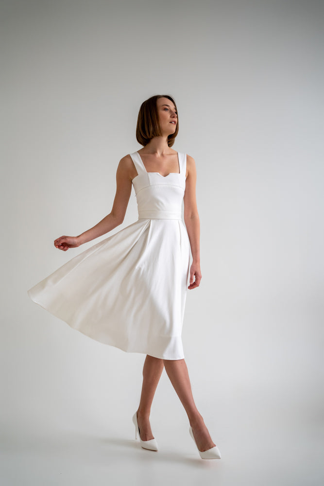 Clear white skirt has an A-lined shape and pockets. This skirt is a separate part of the transformable dress set so later on you can add any top of your choice and connect the both parts with snaps. This skirt is perfect for everyday occasions as well as office wear and more special events depending on accessories you choose to pair this piece of clothing with. White dress. Woman in white dress
