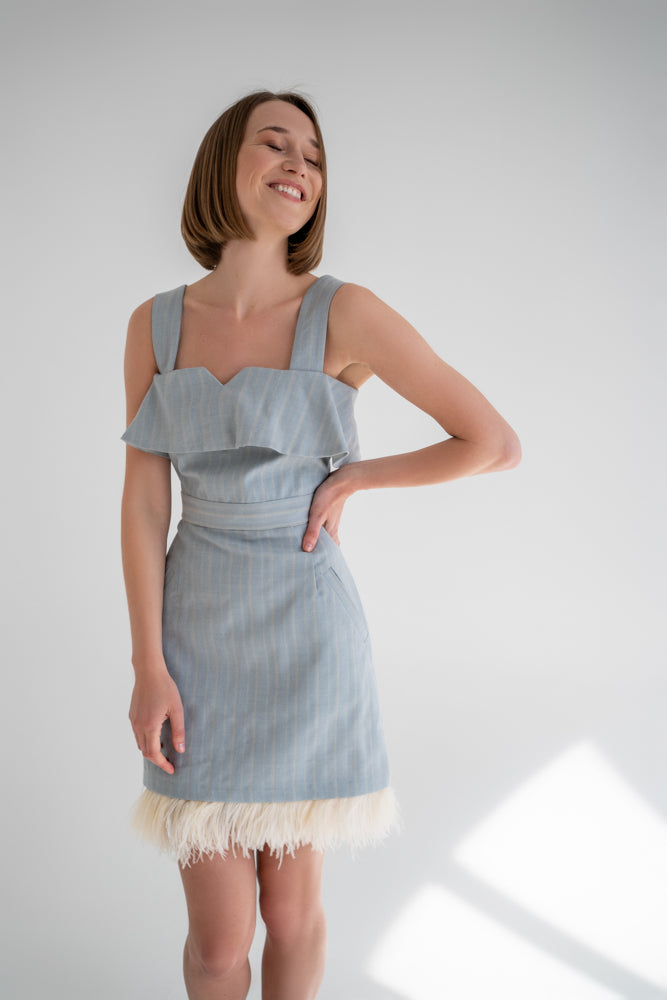 beautiful woman laughing in a two-piece feather dress - it consists of a light blue ruffled corset top and a feather mini skirt